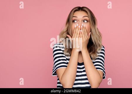 Lustige aufgeregt junge Mädchen decken offenen Mund schauen Seite, um Platz in Aufregung und positiven Schock zu kopieren Stockfoto