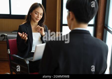 Schöne behinderte Geschäftsfrau treffen mit ihrem Chef in der Sitzungssaal. Büromädchen im Rollstuhl Stockfoto