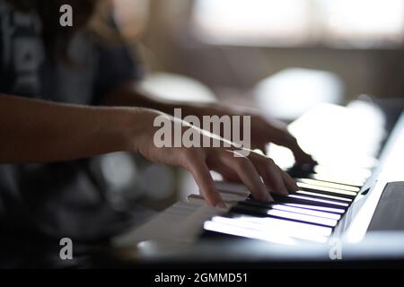 Die Hände des Musikers auf dem Synthesizer. Ein zugeschnittenes Bild einer Person, die einen Synthesizer spielt. Seitenansicht. Hochwertige Fotos Stockfoto