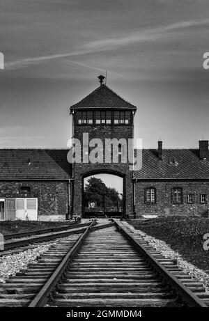 Auschwitz, Polen - 15. September 2021: Schwarz-weiß-Ansicht des Torhauses und der Bahngleise im Konzentrationslager Auschwitz in Polen Stockfoto