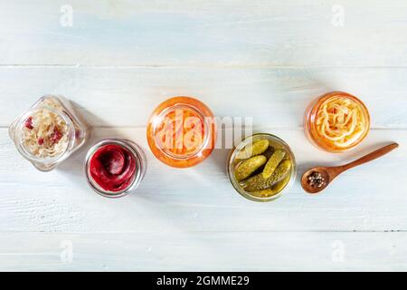 Fermentierte Lebensmittel. Gemüsekonserven. Eingelegte Karotte, Rote Beete, Sauerkraut und andere Bio-Konserven in Maurergrüsern, von oben auf rustikalem Holzhintergrund geschossen Stockfoto