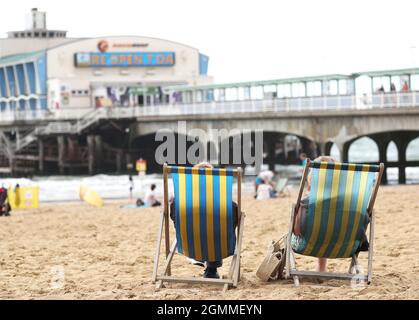 Aktenfoto vom 9/8/2019 von zwei Personen, die in Liegestühlen am Pier am Bournemouth Beach in Dorset sitzen. Fast die Hälfte (47 %) der Arbeitnehmer weiß nicht, wie sie ihren Ruhestand planen sollen, hat eine Umfrage ergeben. Laut Aviva fühlen sich Frauen fast doppelt so wahrscheinlich wie Männer, wenn sie sich auf den Ruhestand vorbereiten und sparen, mit 21 % gegenüber 12 %. Ausgabedatum: Montag, 20. September 2021. Stockfoto