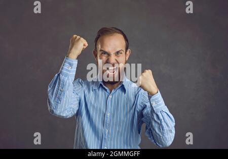 Studio-Porträt eines wütenden, aggressiven, frustrierten Mannes, der Fäuste zusammenhält und schreit Stockfoto