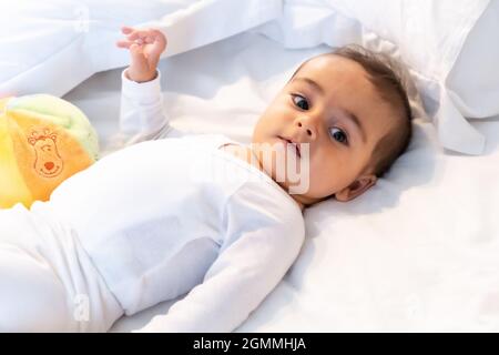 Ich wachte gerade auf entzückendes 5 Monate altes kaukasisches Baby lächelnd in einem grauen T-Shirt und einem Ball zum Spielen Stockfoto