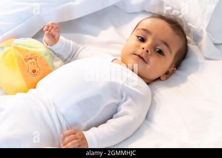 Ich wachte gerade auf entzückendes 5 Monate altes kaukasisches Baby lächelnd in einem grauen T-Shirt und einem Ball zum Spielen Stockfoto