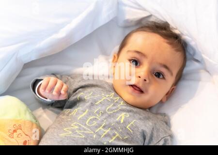 Ich wachte gerade auf entzückendes 5 Monate altes kaukasisches Baby lächelnd in einem grauen T-Shirt und einem Ball zum Spielen Stockfoto