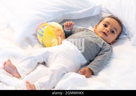 Ich wachte gerade auf entzückendes 5 Monate altes kaukasisches Baby lächelnd in einem grauen T-Shirt und einem Ball zum Spielen Stockfoto