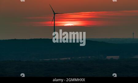 Die untergehende Sonne und einige Windkraftanlagen im Ruhrgebiet, von der Halde Haniel, Bottrop, Nordrhein-Westfalen, Deutschland, aus gesehen Stockfoto