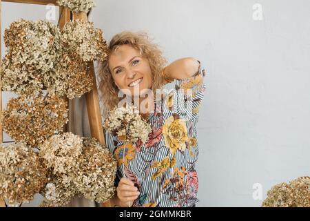 Portrait einer schönen blonden Frau, Innenarchitekt Floristin, lächelnd Blick in den Rahmen. Copy Raum. Natürliche Dekor Konzept im Herbst. Stockfoto