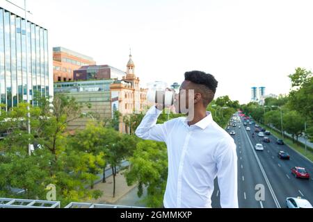 Porträt junger afroamerikanischer Geschäftsführer, der auf der Straße Kaffee trinkt Stockfoto