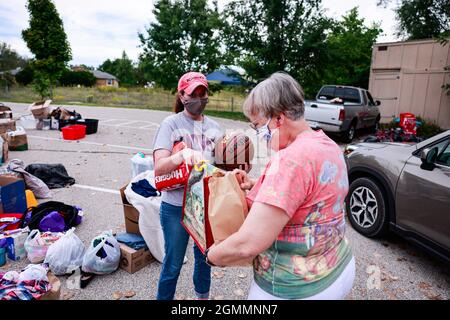 Amanda Roshan-Rawaan, links, nimmt eine Spende für afghanische Flüchtlinge an der Unitarian Universalist Church in Bloomington entgegen. Derzeit befinden sich über 6000 Flüchtlinge in einem sicheren Gebiet von Camp Atterbury, einem Militärstützpunkt in der Nähe von Edinburgh, Ind. Die Regierung der Vereinigten Staaten hat eine militärische Luftbrücke von über 100,000 Afghanen ermöglicht, die nach der raschen Übernahme Afghanistans durch die Taliban als gefährdet gelten. Die USA zogen sich nach ihrem längsten Krieg, der 2001 nach dem Terroranschlag von 9/11 begann, aus Afghanistan zurück. Stockfoto