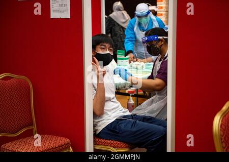 Kuala Lumpur, Malaysia. September 2021. Ein Junge erhält eine Dosis COVID-19-Impfstoff, da Malaysia beginnt, Impfungen für Jugendliche im Alter von 12 bis 17 Jahren in Shah Alam im Bundesstaat Selangor, Malaysia, am 20. September 2021, durchzuführen. Malaysia meldete am Mitternachtssonntag weitere 14,954 neue COVID-19-Infektionen, was die landesweite Gesamtzahl nach Angaben des Gesundheitsministeriums auf 2,097,830 beläuft. Das Land hat am Sonntag 219,081 COVID-19-Dosen verabreicht, und rund 67.4 Prozent der Bevölkerung haben mindestens eine Dosis erhalten und 56.5 Prozent sind vollständig geimpft. Quelle: Chong Voon Chung/Xinhua/Alamy Live News Stockfoto