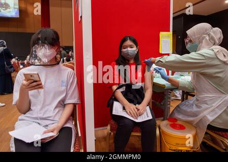 Kuala Lumpur, Malaysia. September 2021. Ein Mädchen erhält eine Dosis COVID-19-Impfstoff, da Malaysia beginnt, Impfungen für Jugendliche im Alter von 12 bis 17 Jahren in Shah Alam im Bundesstaat Selangor, Malaysia, am 20. September 2021, durchzuführen. Malaysia meldete am Mitternachtssonntag weitere 14,954 neue COVID-19-Infektionen, was die landesweite Gesamtzahl nach Angaben des Gesundheitsministeriums auf 2,097,830 beläuft. Das Land hat am Sonntag 219,081 COVID-19-Dosen verabreicht, und rund 67.4 Prozent der Bevölkerung haben mindestens eine Dosis erhalten und 56.5 Prozent sind vollständig geimpft. Quelle: Chong Voon Chung/Xinhua/Alamy Live News Stockfoto