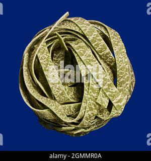 Nahaufnahme Nest von ungekochten Spinat fettuccini Nudeln auf blauem Hintergrund Stockfoto