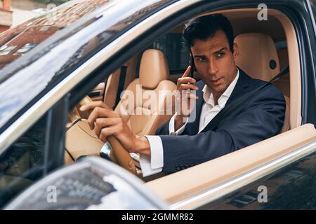 Geschäftsführer, der vom Auto aus telefoniert Stockfoto