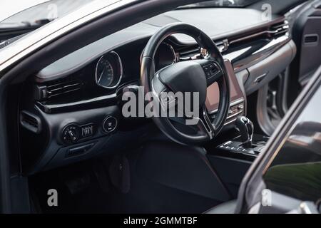 Armaturenbrett und Lenkrad mit Tasten zur Mediensteuerung. Schwarzes Cockpit. Innenraum von Luxusfahrzeugen. Hintergrund zum Thema Autos. Stockfoto