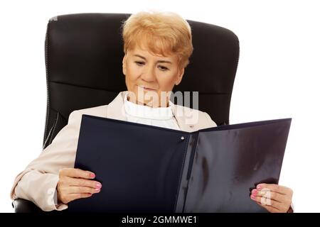 Ältere kaukasische Geschäftsfrau mit einem Rekordbuch sitzenden Stuhl auf weißem Hintergrund Stockfoto