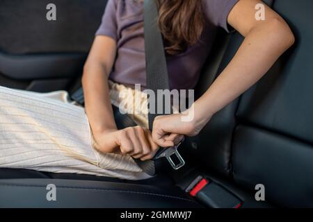 Kleines Mädchen, das den Sicherheitsgurt befestigt, während es auf dem Rücksitz eines Elektroautos sitzt Stockfoto