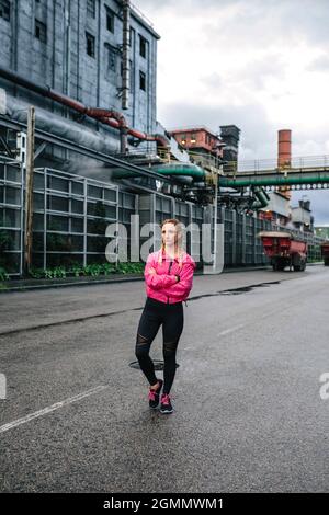 Sportliche Frau, die vor einer Fabrik posiert Stockfoto