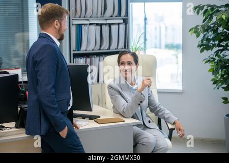 Glückliche junge Geschäftsfrau und Geschäftsmann, die am Arbeitsplatz im Büro diskutieren Stockfoto
