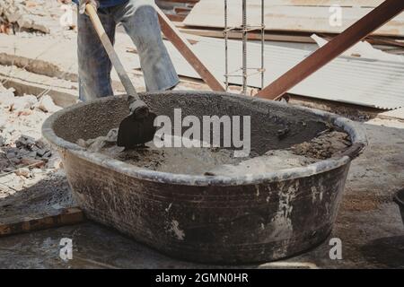 Arbeiter Mann Hausbauer mischen Mörtel aus einem Trog in Eimer Stockfoto