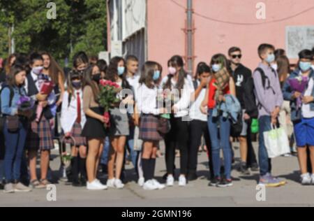 Schüler mit Gesichtsmasken oder ohne auf einer Zeremonie auf dem Schulhof am ersten Schultag am 15. September 2021 Stockfoto