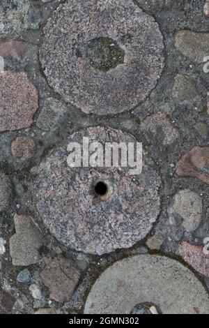 Alte graue Steinmauer, alte graue Steinstraße, alte Granitmühlen in Mauerwerk. Hintergrundbild. Stockfoto