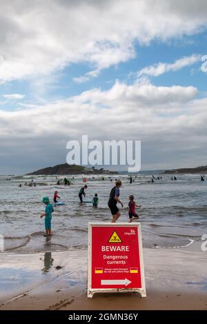 Am Bantham Beach in Devon warnt ein RNLI-Schild Schwimmer vor gefährlichen Strömungen. Es wird von vielen Menschen ignoriert. Stockfoto