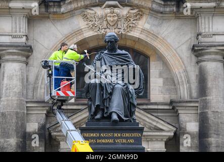 20. September 2021, Sachsen, Dresden: Mitarbeiter der Firma Fuchs und Girke erhalten das Denkmal „Friedrich August der Gerechte“ vor dem Ständehaus mit heißem Wachs. Die Skulptur von Ernst Rietschel, die König Friedrich August I. sitzend zeigt, steht seit Mai 2008 an dieser Stelle und wird seit heute jährlich überprüft. In den kommenden Tagen werden die Denkmäler von Luther und König Friedrich August II. Auf dem Neumarkt und das Körner-Denkmal auf dem Georgplatz auf Schäden überprüft und behandelt. Foto: Robert Michael/dpa-Zentralbild/ZB Stockfoto