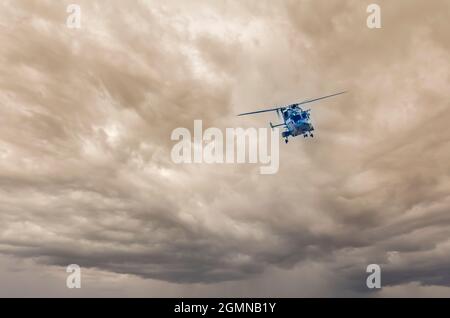 Der von Hindustan Aeronautics Limited entwickelte fortschrittliche leichte Hubschrauber Dhruv fliegt vor dem Hintergrund grauer, stürmischer Monsunwolken. Stockfoto