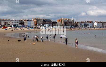 Editorial Weymouth, Großbritannien - 11. September 2021: Urlauber auf dem sanft geschwungenen Sandbogen in der Weymouth Bay und der Esplanade in der Stadt Weymou Stockfoto