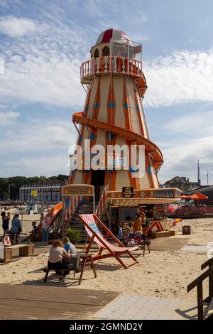 Editorial Weymouth, UK - 11. September 2021:Eine Sommerszene am Weymouth Beach in England mit einer Helter Skelter-Folie. Stockfoto