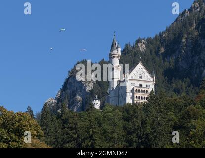 Schloss Neuschwanstein, Bayern, Gemany (mit drei Gleitschirmen, die oben im Himmel schweben). Stockfoto