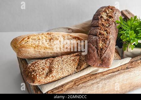 Brotauswahl in einer alten Holzkiste. Verschiedene Arten von Grüns für Brot. studiofoto. Stillleben Stockfoto