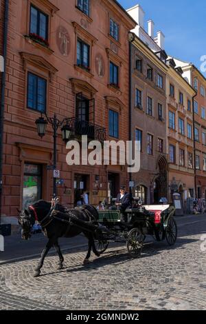 Warschau, Polen - 11. September 2021: Schwarzes Pferd und Kutsche auf einer gepflasterten Straße in der historischen Altstadt von Warschau Stockfoto