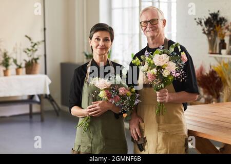 Waist up Porträt von reifen Paar mit Blumen in Blumenladen und Blick auf die Kamera Stockfoto