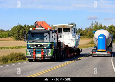 Grüner Volvo FM Sattelanhänger transportiert Freizeitboot als Übergröße Last, Tankwagen fährt in entgegengesetzte Richtung. Salo, Finnland. 9. September 2021 Stockfoto