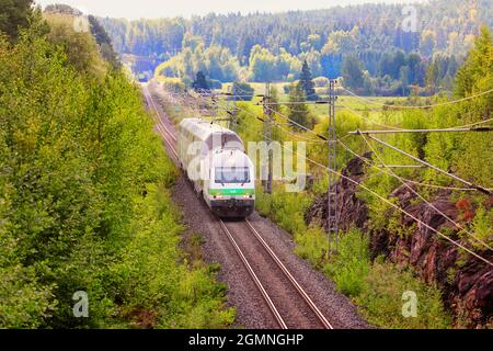 Grüne Frühherbstlandschaft mit VR Intercity Zug in Geschwindigkeit, Tunnel im Hintergrund. Salo, Finnland. 29. August 2021. Stockfoto