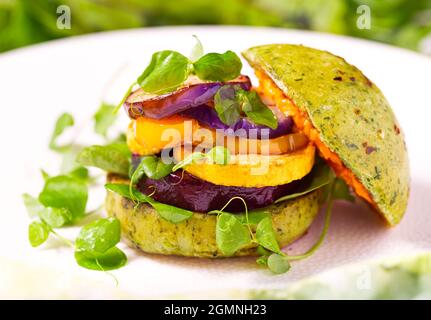 Gesunder veganer Burger auf pflanzlicher Basis mit geröstetem Gemüse auf einem mit Spianch infundierten Brötchen Stockfoto