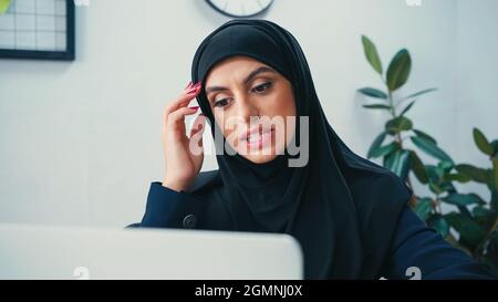 Verwirrt muslimische Frau in Hijab Blick auf verschwommene Laptop Stockfoto