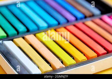 Helle, farbenfrohe neue Buntstifte oder Kreidepastellfarben in einer Box aus der Nähe. Selektiver Fokus. Nahaufnahme Stockfoto
