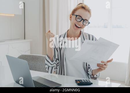 Überglücklich Rothaarige Frau, die ja ausrief, Geldrückerstattung oder letzte Hypothekenzahlung feierte Stockfoto