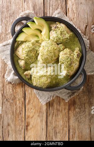 Guatemaltekischer grüner Hühnereintopf ist häufiger als Hühnereintopf bekannt, bei dem Tomatillos in der Nähe auf dem Teller auf dem Tisch liegen. Vertikale Draufsicht von oben Stockfoto