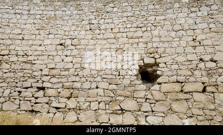Ein Loch in der alten Steinmauer der Festung. Mauerwerk aus Naturstein. Stockfoto