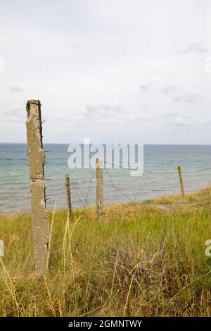 Stahlbetonpfosten mit gestrecktem altem Stacheldraht. Blick auf das Schwarze Meer. Stockfoto