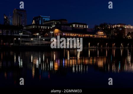 Die Altstadt von Sacramento bei Nacht in der Nähe von Weihnachten, von der anderen Seite des Sacramento River aus gesehen, mit Weihnachtslichtern, die sich am 2020. Dezember auf dem Fluss spiegeln Stockfoto