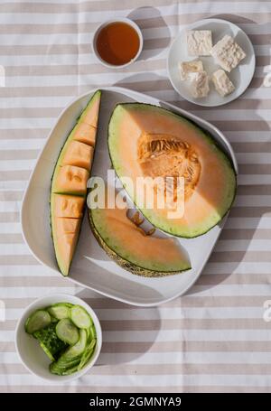 Frische Melonen in Scheiben geschnitten auf Tischdecke. Freier Speicherplatz für Text. Draufsicht. Melone aus japanischen Melonen, Honigmelone oder Cantaloupe Cucumis melo auf Holzlasche geschnitten Stockfoto