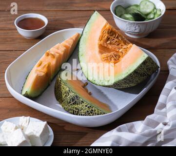 Frische Melonen in Scheiben auf Holztisch. Freier Speicherplatz für Text. Draufsicht. Melone aus japanischen Melonen, Honigmelone oder Cantaloupe Cucumis melo auf Holz geschnitten Stockfoto