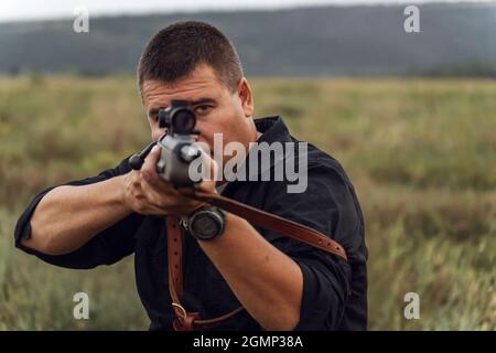 Porträt eines Schützen mit einem Gewehr. Europäer schießt ein Gewehr mit einem optischen Blick. Nahaufnahme Stockfoto