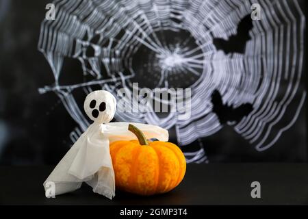 Weißer Geist sitzt auf dem Ast vor dem Hintergrund von Spinnweben und Fledermäusen. Konzept von halloween . Stockfoto